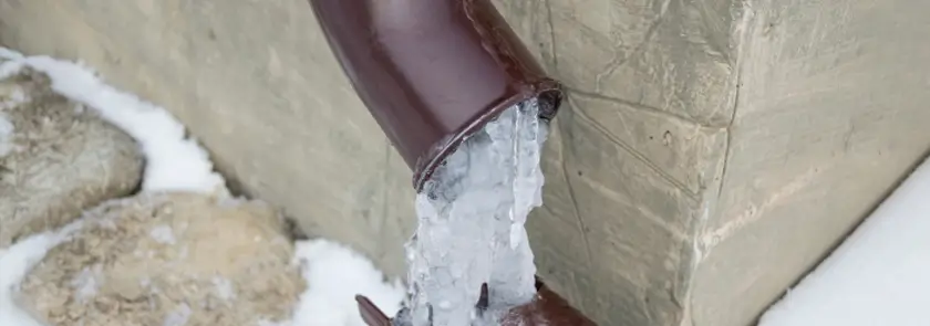 Exposed plumbing pipe frozen solid with ice expansion, indicating risk of burst or water supply blockage