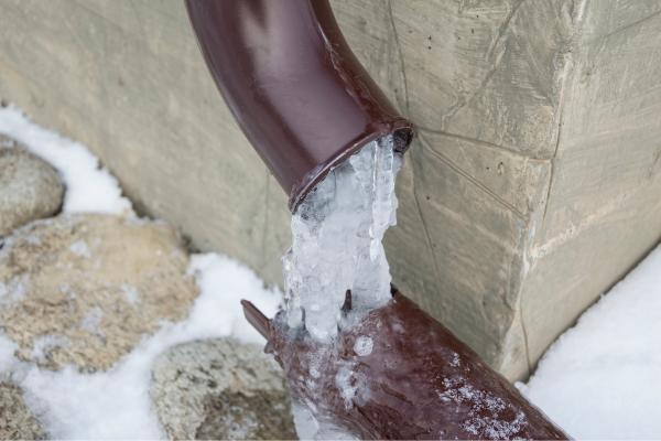 Exposed plumbing pipe frozen solid with ice expansion, indicating risk of burst or water supply blockage